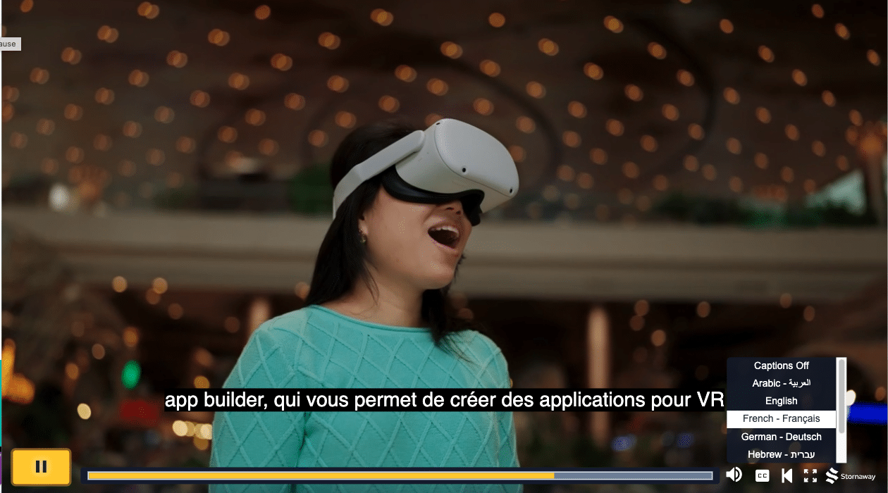 An Asian woman with straight, dark brown hair wears a teal sweater women is wearing a VR headset looks amazed. French subtitles displaying on the bottom and a the closed caption menu open in the bottom right for the viewer to select a new language.